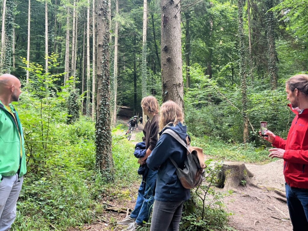 Im Konstanzer Stadtwald wurde das Projektteam von Försterin Irmgard Weishaupt begleitet. Zu sehen ist der Mountainbiketrail der durch den Stadtwald verläuft. Ein Mountainbiker fährt gerade an dem Projektteam vorbei. Im Bild zu sehen (von links: Volker Kromrey, Pascal Solbach (beide Bodensee-Stiftung), Franziska Schlemmer (Hochschule für Forstwirtschaft Rottenburg), Andreas Ziermann (Bodensee-Stiftung).
