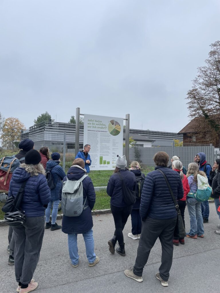 Die Gruppe steht vor dem Infoschild des Weltackers.