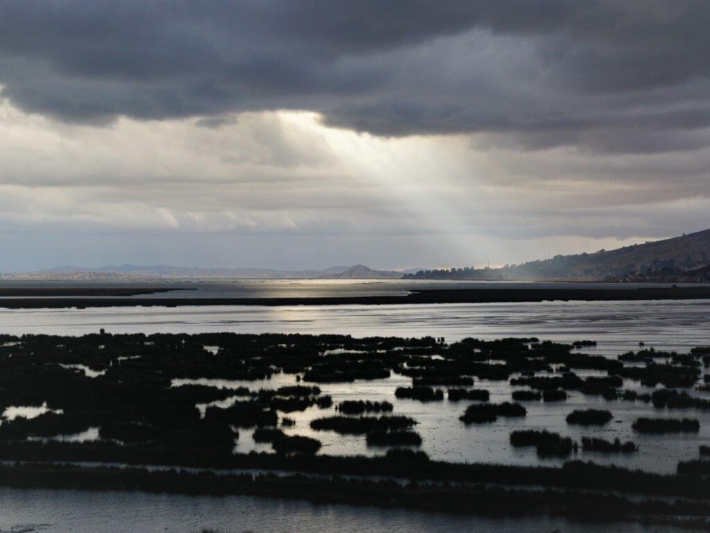 Blick auf den Titicaca-See unter dunklen Wolken.