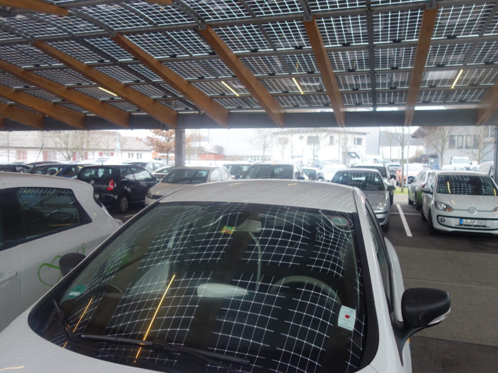 Blick von unten nach oben auf Solarpaneelen, die einen Parkplatz überdachen.